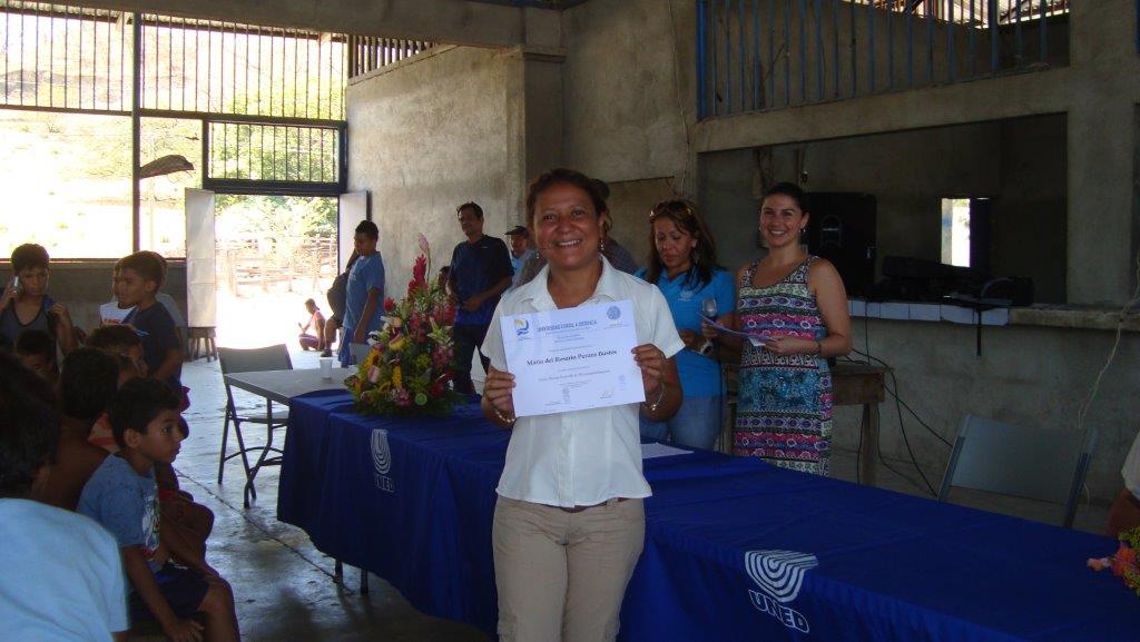 Mujer de área rural recibiendo un título de un programa de extensión de las universidades