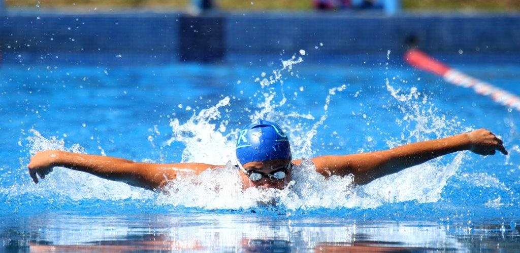 Joven en competencia de natación estilo mariposa.