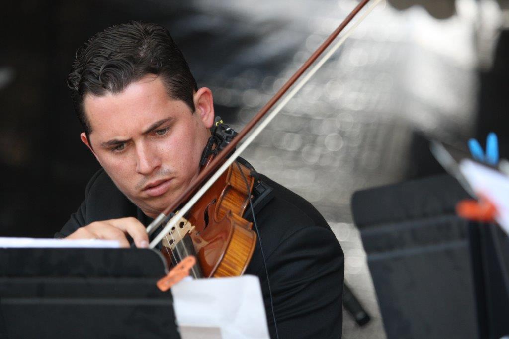 Joven que participa en una representación musical, toca el violín.